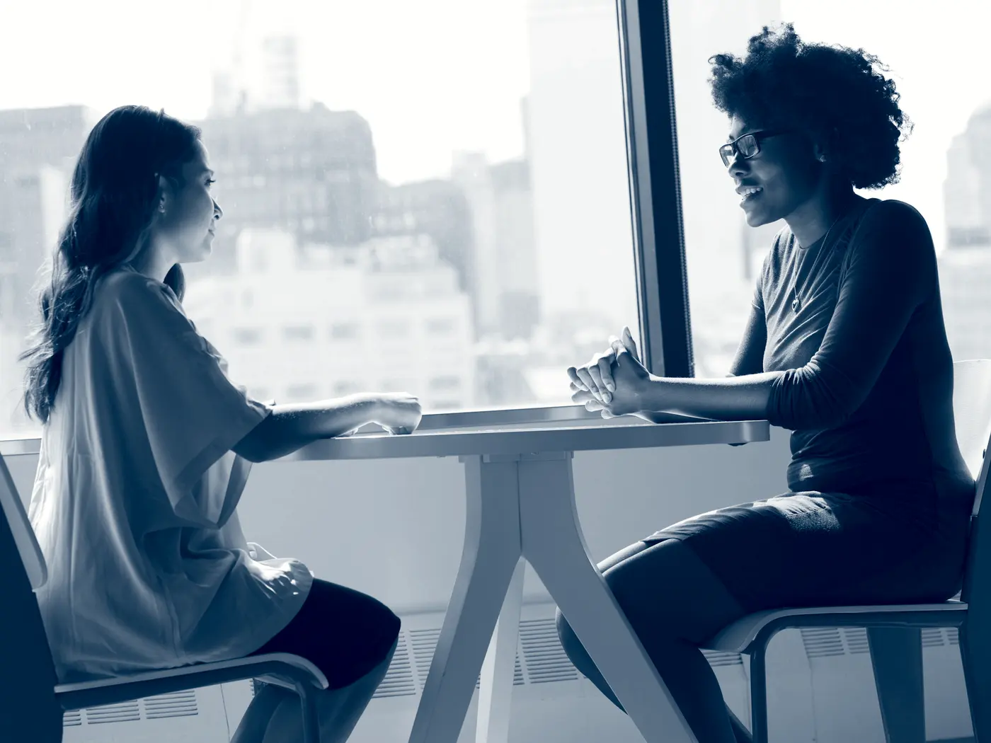 Twee mensen in gesprek tegenover elkaar aan een tafel.